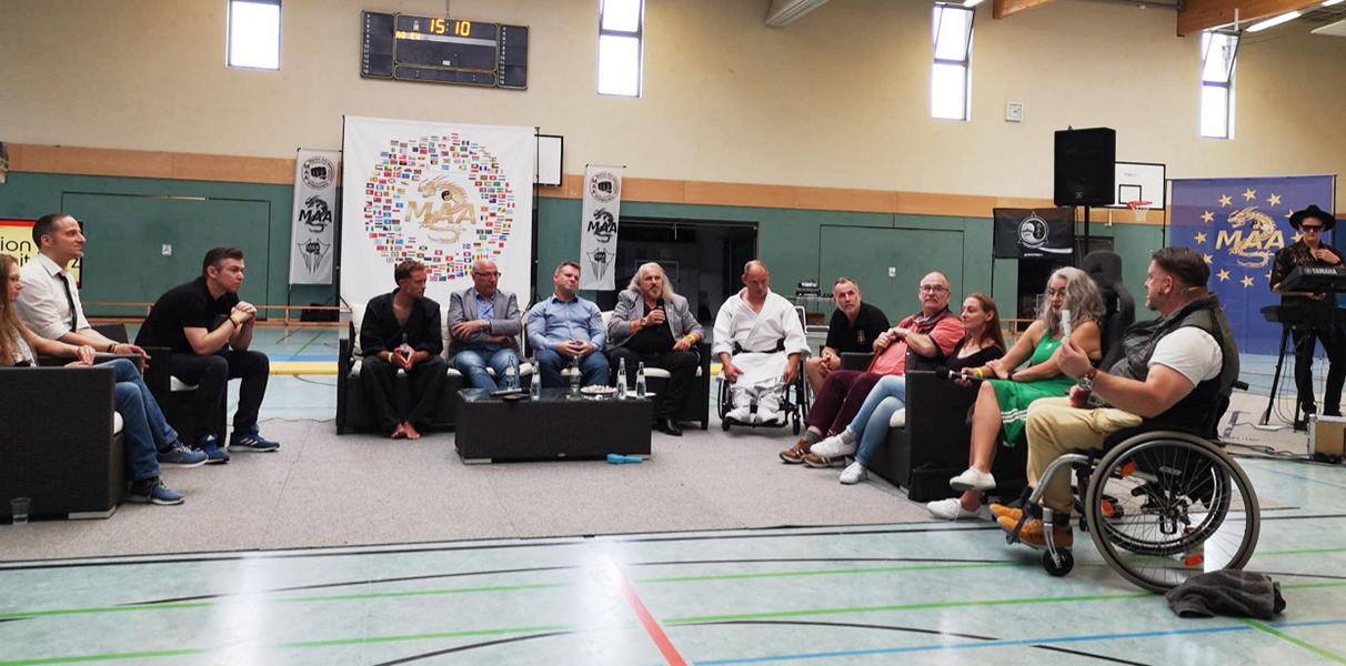 Inklusion mit Herz. TeilnehmerIn am Gespräch sitzen in einer Sporthalle im Halbkreis. Als eines der interessantesten Themen auf dem Talksofa kristallisierte sich "Miteinander statt Gegeneinander" heraus.